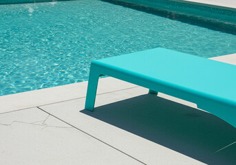 Turquoise Poolside Lounger Beside a Sparkling Blue Swimming Pool Offers Relaxation and Summer Vacation Vibes