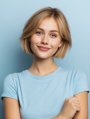 A cheerful young woman with a confident smile poses against a light blue background, exuding positivity and warmth.