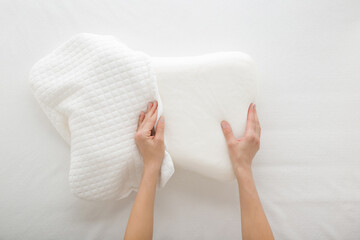 Young adult woman hands changing white cotton cover on soft memory foam pillow on mattress background. Closeup. Point of view shot. Top down view.