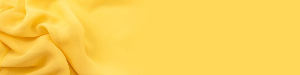 The background of the banner for the site from a piece of fabric. Texture of silk or satin fabric in yellow color. Textile