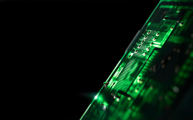 Close-up of an illuminated green electronic circuit board with many electrical components, isolated...
