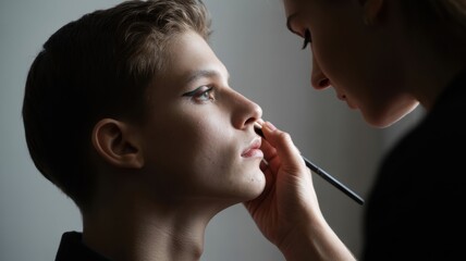 Female makeup artist applying eyeliner on young caucasian male model