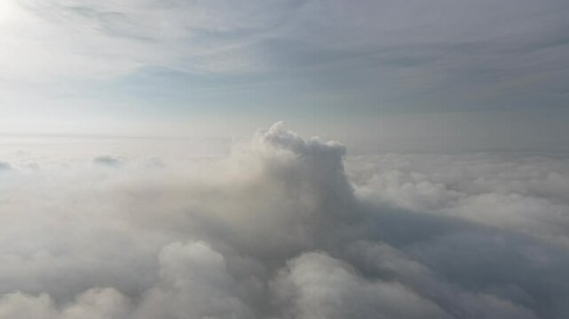 A stunning aerial view capturing the serene beauty of clouds from above. Soft, billowing formations stretch across the sky, bathed in golden sunlight.