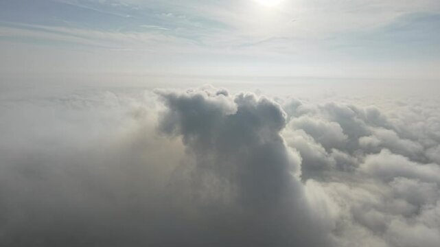 A stunning aerial view capturing the serene beauty of clouds from above. Soft, billowing formations stretch across the sky, bathed in golden sunlight.
