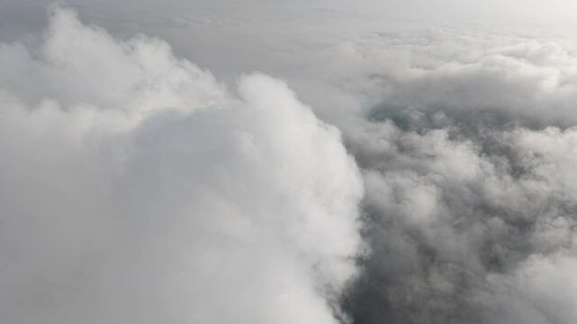 A stunning aerial view captures the serene beauty of clouds from above. Soft, billowing formations stretch across the sky, bathed in golden sunlight.