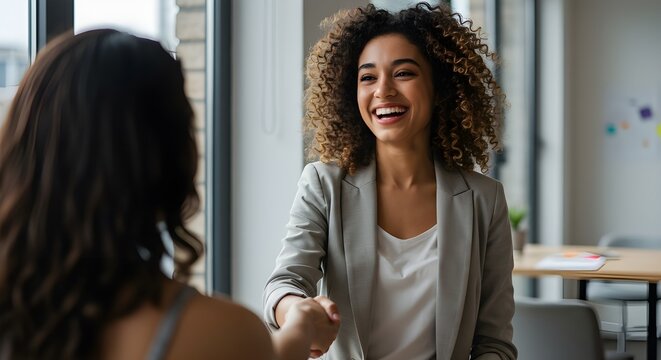 Un apret&oacute;n de manos entre una empresaria o gerente de recursos humanos feliz, segura y entusiasmada y una colega, socia o empleada. Un acuerdo, trato o reuni&oacute;n con un compa&ntilde;ero de trabajo en la sala d