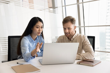 Colleagues discussing topics related to their work, considering received information, exploring software using laptop. Manager selling company services, showing presentation during meeting with client