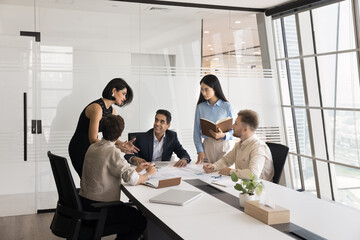 Project managers brainstorming on marketing business strategy, gathered at conference table in modern office. Professional team analyzing papers, reviewing reports or statistical data. Briefing event