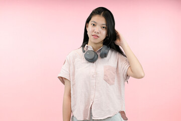 young asian woman with confident and relax wearing headphone in studio pink background