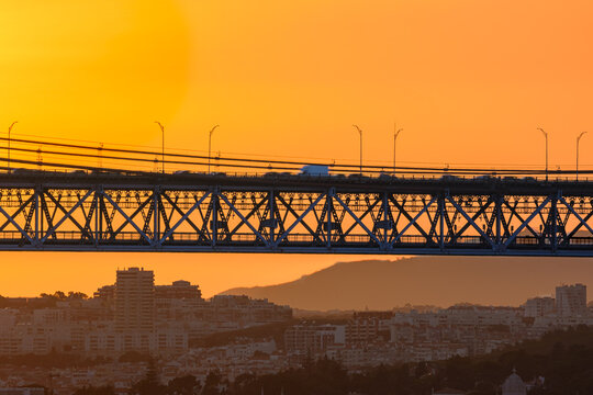 Sunset view of suspension bridge with vehicles and cityscape in
