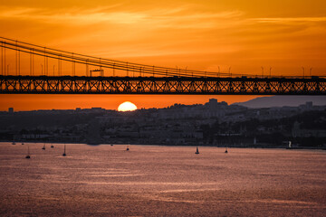 25 de Abril bridge over Tagus river at sunset with sailboats and