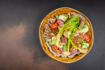 Gourmet salad with grilled beef, lettuce, cucumber ribbons, cherry tomatoes, pine nuts, and crispy quinoa chips served in a ceramic bowl