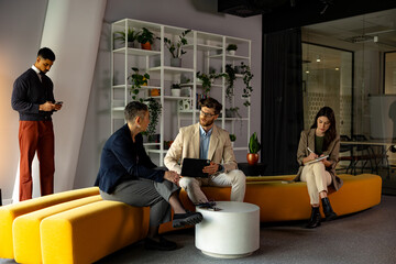 Business colleagues sharing ideas and working together, using tablet and taking notes during a meeting in a modern office