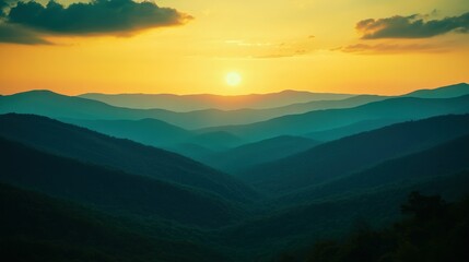 Fototapeta premium A beautiful sunset over layered green and blue mountain ranges