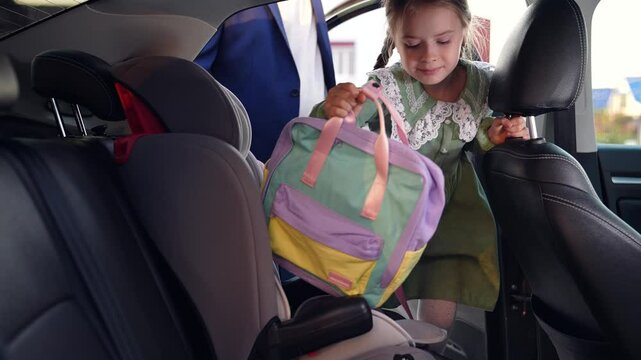 father picks up his little daughter from school. child kid father. car take child home after school. put little child in the car seat. happy family. father parent places child chair back seat.