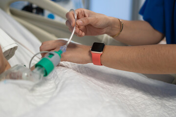Nurse adjusting iv drip of patient in hospital bed