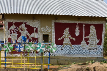 A wall adorned with intricate Alpana art, depicting figures and patterns.