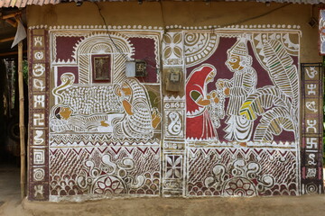 A wall adorned with intricate Alpana art, depicting figures and patterns.
