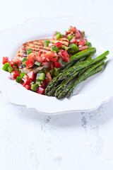 Grilled chicken fillet with asparagus and tomato salsa. Close up.	