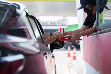 A customer picks up a French fries burger from a drive-thru counter employee during rush hour.