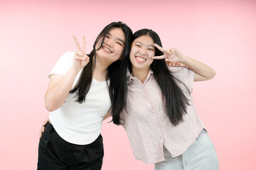 Fototapeta na wymiar two best friend asian woman posing with peace signs in studio background