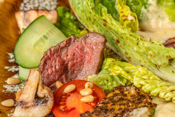 Juicy medium-rare beef salad with fresh vegetables, mushrooms, and pine nuts