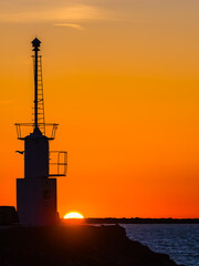 Beautiful sunset over the coast with a lighthouse silhouetted in Sweden