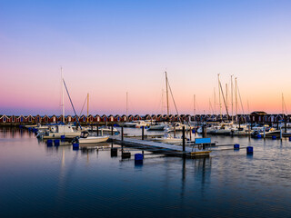 Sunset over Träslövsläge Harbour with boats and colorful houses reflecting in calm waters