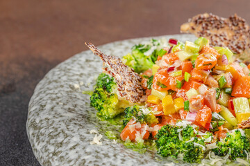 Colorful salmon tartare with diced vegetables, fresh herbs, and roasted broccoli.