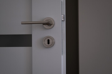 Close-up of a metal door handle on a white interior door.