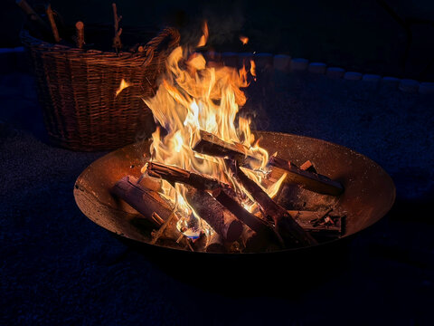 burning wood in a fire bowl with a basket in the background