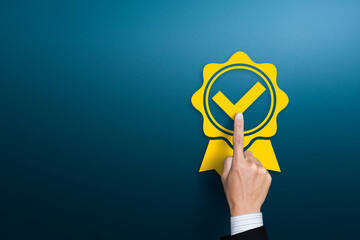 Businessman pushing rosetted award medal with check mark tick label, approved check mark ribbon,...