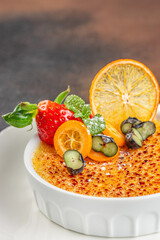Classic creme brulee topped with fresh berries, citrus slices, and mint leaves