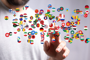 A hand interacts with a digital display of flags representing global connection and international...