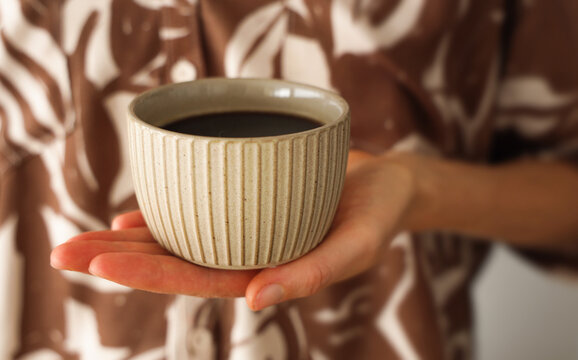 Woman's hand hold a fresh cup of coffee. Closeup on coffee cup in french pastry shop.