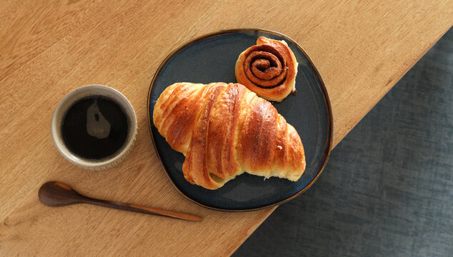 Breakfast view a bunch of croissant and a cup of coffee with cafe vibe background. Cafe menu, breakfast. Fresh pastries: croissants, rolls.