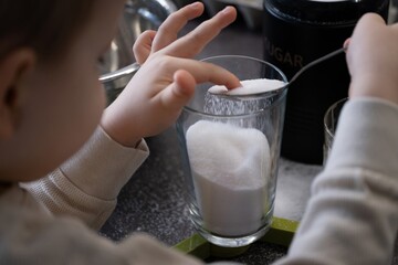 Child touching sugar with finger in a glass jar