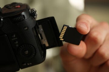 Man inserting SD memory card into photo camera, closeup