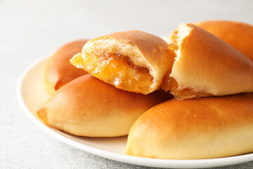 Tasty baked patties with orange jam on light grey table, closeup