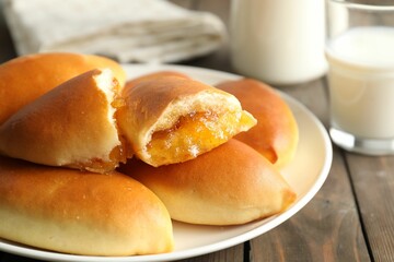 Tasty baked patties with orange jam on wooden table, closeup