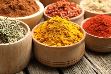 Different aromatic spices in bowls on wooden table, closeup