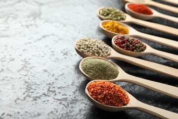 Many different spices in spoons on black table, closeup. Space for text