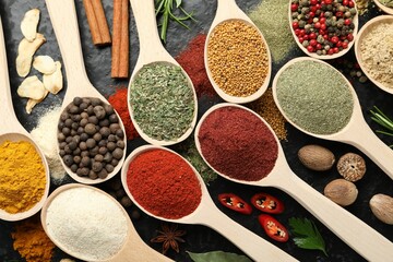 Many different spices in spoons on grey table, flat lay