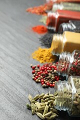 Different aromatic spices in jars on black table, closeup