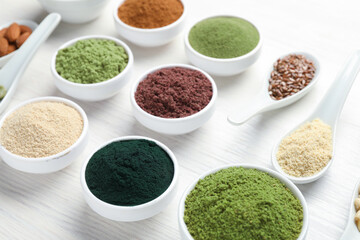 Different superfood powders on white wooden table, closeup