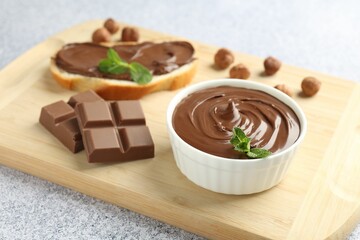 Tasty chocolate hazelnut spread with mint in bowl on grey textured table, closeup