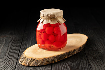 Jar of Pickled Cherries on Dark Wooden Background