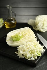 Cut Chinese cabbage and knife on black table, closeup