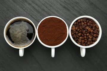 Aromatic ground coffee, beans and hot drink on black table, flat lay
