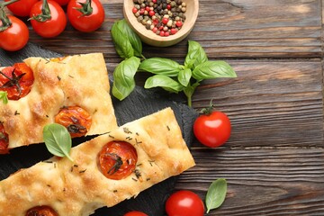 Pieces of delicious focaccia with tomatoes and spices on wooden table, flat lay